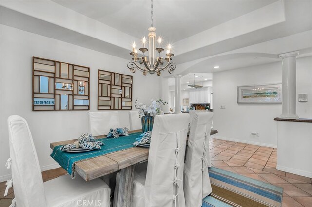 tiled dining room with baseboards, an inviting chandelier, a tray ceiling, decorative columns, and arched walkways