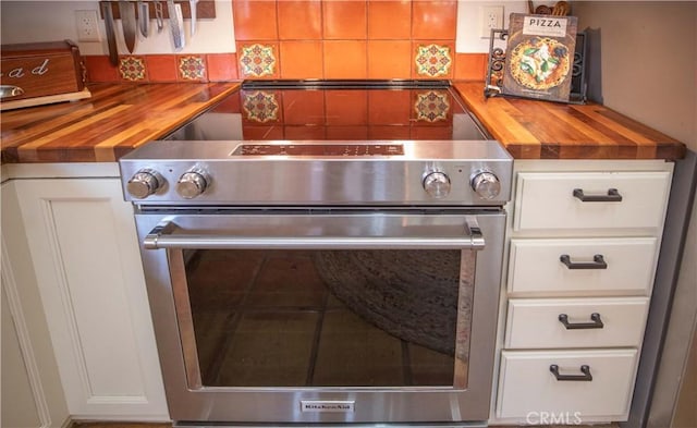interior details featuring wooden counters, decorative backsplash, stainless steel electric stove, and white cabinetry