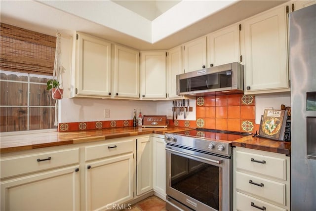 kitchen with stainless steel appliances, butcher block counters, and decorative backsplash