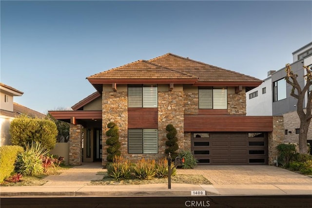 view of front of home featuring a garage, driveway, and stone siding