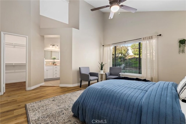 bedroom featuring a spacious closet, high vaulted ceiling, wood finished floors, and baseboards