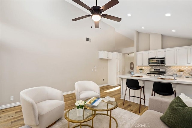 living area featuring visible vents, baseboards, light wood finished floors, and a ceiling fan