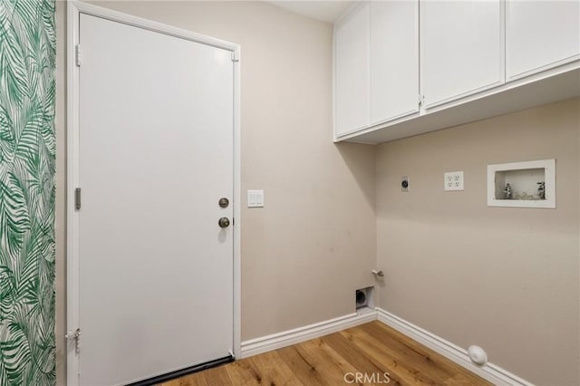 clothes washing area featuring light wood-type flooring, electric dryer hookup, baseboards, washer hookup, and cabinet space