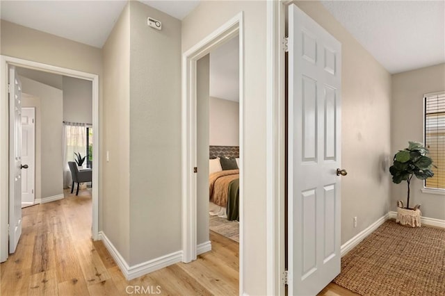 corridor with light wood finished floors and baseboards