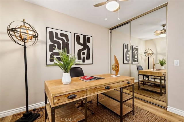 home office featuring ceiling fan, light wood-type flooring, and baseboards