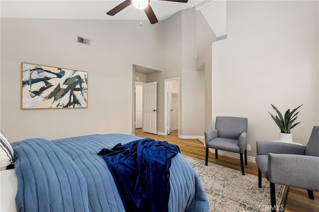 bedroom with visible vents, baseboards, a ceiling fan, wood finished floors, and high vaulted ceiling