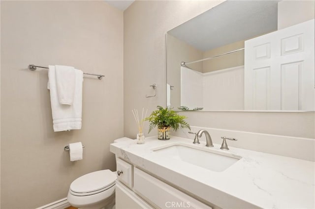 bathroom with toilet, vanity, and baseboards