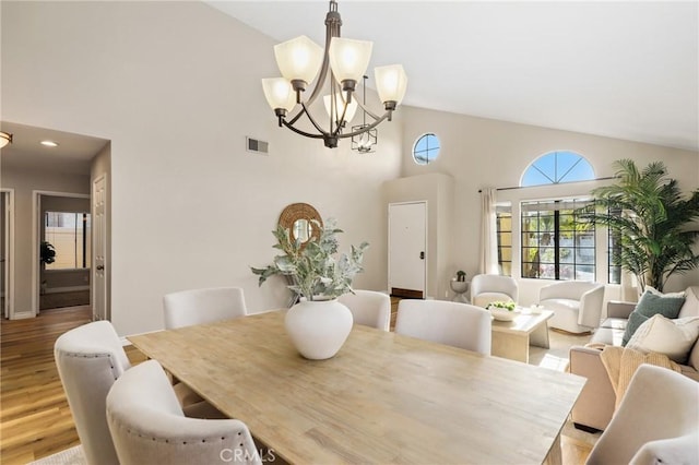 dining area with a chandelier, light wood-style floors, high vaulted ceiling, and visible vents