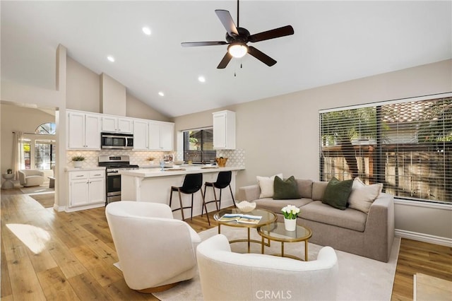 living area featuring high vaulted ceiling, ceiling fan, light wood-style flooring, recessed lighting, and baseboards
