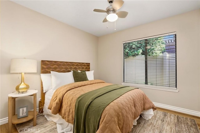 bedroom with ceiling fan, baseboards, and wood finished floors