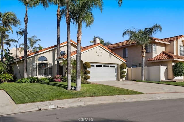 mediterranean / spanish house featuring a tile roof, fence, a garage, and stucco siding