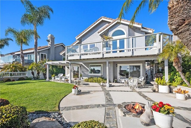 rear view of property featuring a pergola, a balcony, a patio, a lawn, and an outdoor fire pit