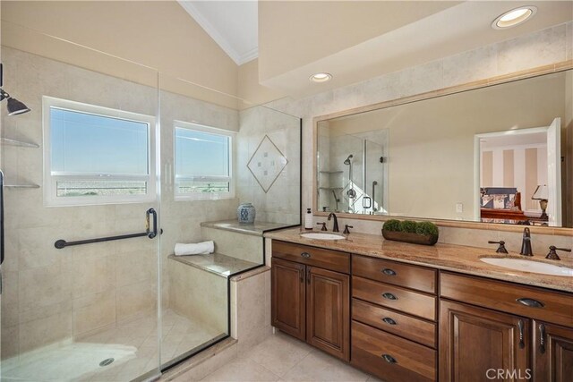 ensuite bathroom with a shower stall, vaulted ceiling, ornamental molding, and a sink