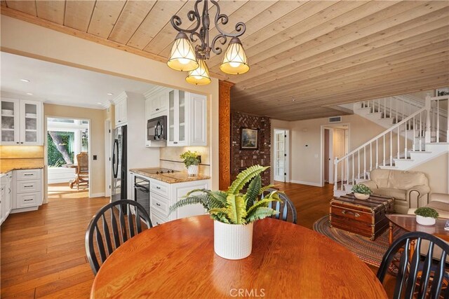 dining room with light wood-style flooring, baseboards, a chandelier, stairway, and wooden ceiling