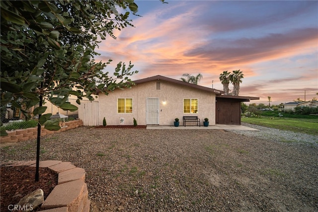 23755 Goetz Dr, Menifee, CA 92587 - property exterior at dusk featuring a patio area, stucco siding, and fence