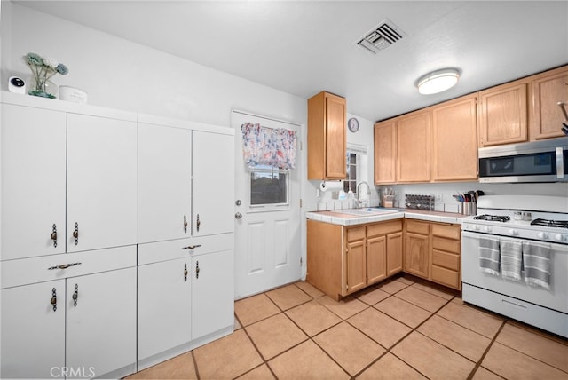 23755 Goetz Dr, Menifee, CA 92587 - kitchen featuring stainless steel microwave, white gas stove, light tile patterned floors, visible vents, and tile countertops