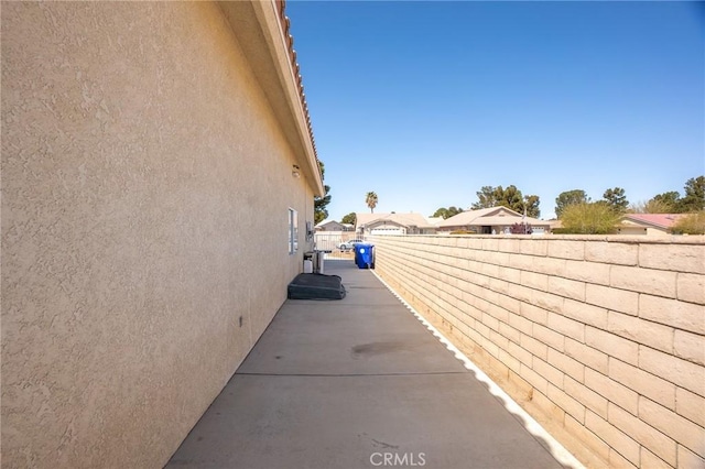 view of property exterior featuring a patio area, fence, and stucco siding