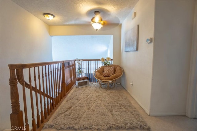 hallway featuring a textured ceiling, baseboards, and carpet floors