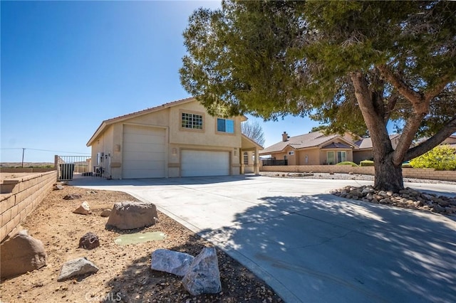 view of front of house featuring driveway, fence, a garage, and stucco siding
