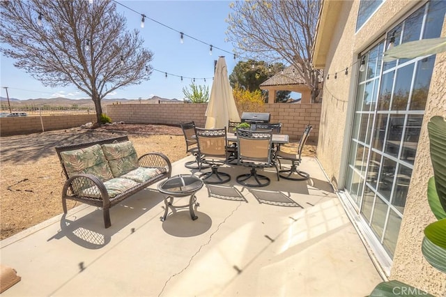 view of patio with outdoor dining space, a fire pit, and a fenced backyard