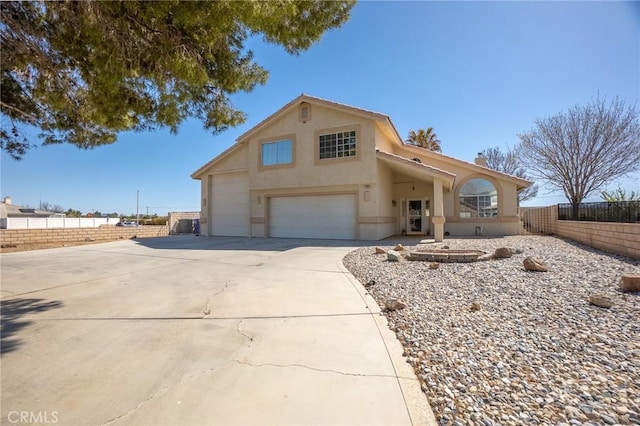 view of front facade with fence, a garage, driveway, and stucco siding