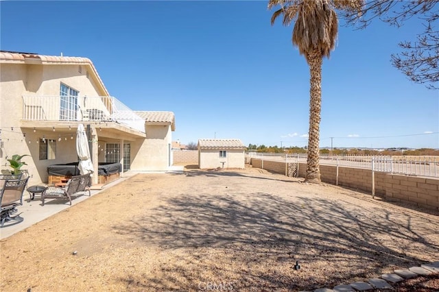 view of yard featuring a storage shed, a fenced backyard, a patio, a balcony, and an outbuilding