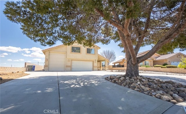 view of front facade featuring an attached garage, fence, driveway, and stucco siding