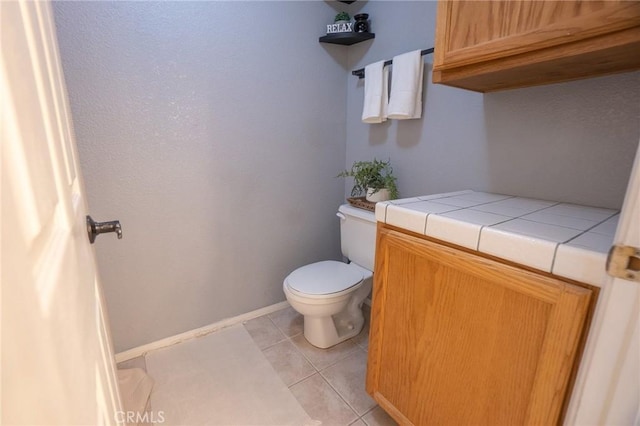 bathroom with toilet, tile patterned floors, and baseboards