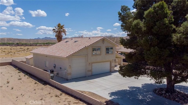 view of front of property with a tiled roof, a mountain view, stucco siding, fence, and driveway