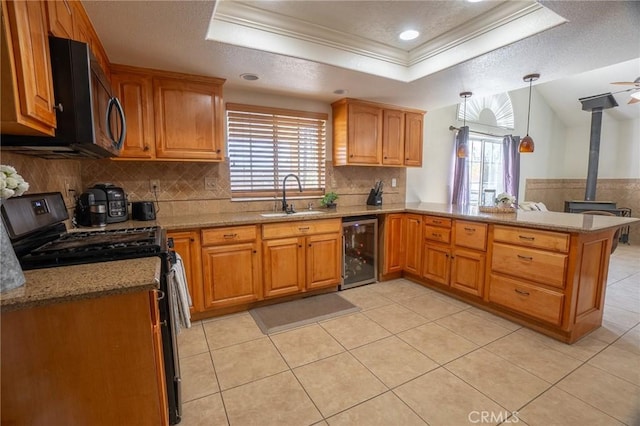kitchen with a raised ceiling, a sink, a wood stove, wine cooler, and gas stove