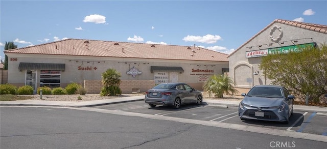 view of front of home featuring a tiled roof, uncovered parking, and stucco siding