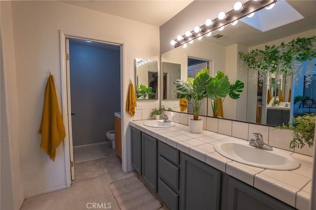 bathroom with double vanity, visible vents, a sink, and toilet