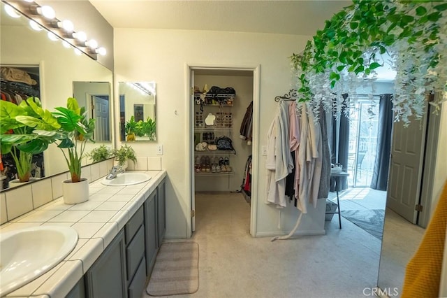 full bathroom featuring a sink, a spacious closet, and double vanity