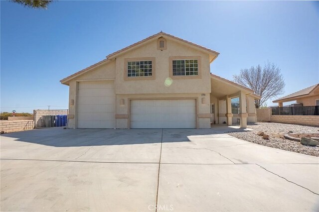view of front of home featuring concrete driveway, fence, and stucco siding