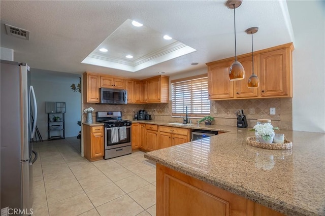 kitchen featuring ornamental molding, visible vents, a tray ceiling, appliances with stainless steel finishes, and a sink