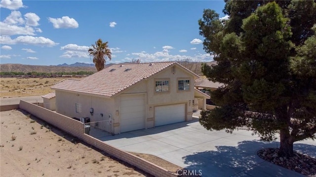 view of front of property with a mountain view, a tiled roof, fence, concrete driveway, and stucco siding