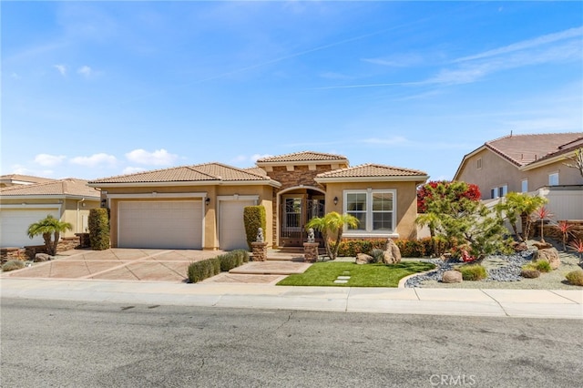 mediterranean / spanish house with stucco siding, driveway, a garage, and a tile roof