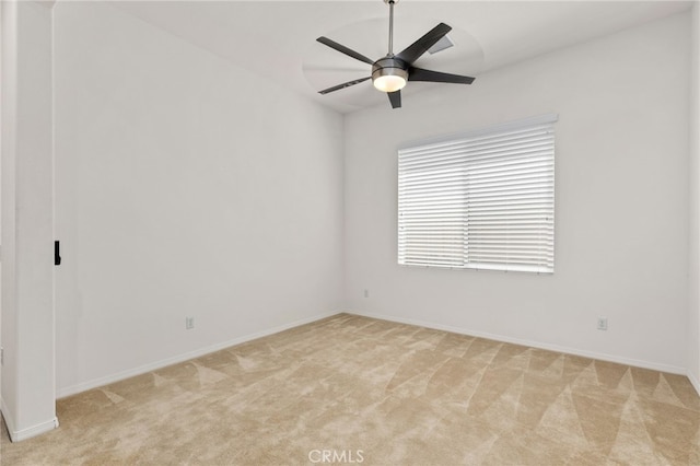 spare room featuring light colored carpet, baseboards, and ceiling fan