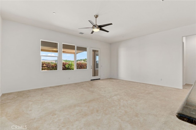 carpeted spare room featuring visible vents and ceiling fan