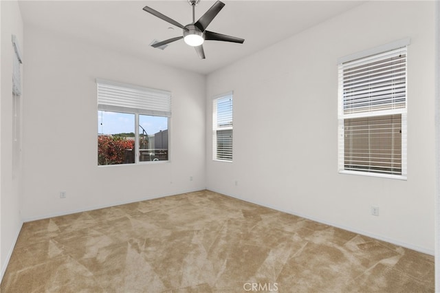 carpeted spare room featuring baseboards and ceiling fan