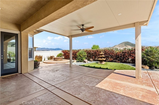view of patio with a ceiling fan, a mountain view, and fence