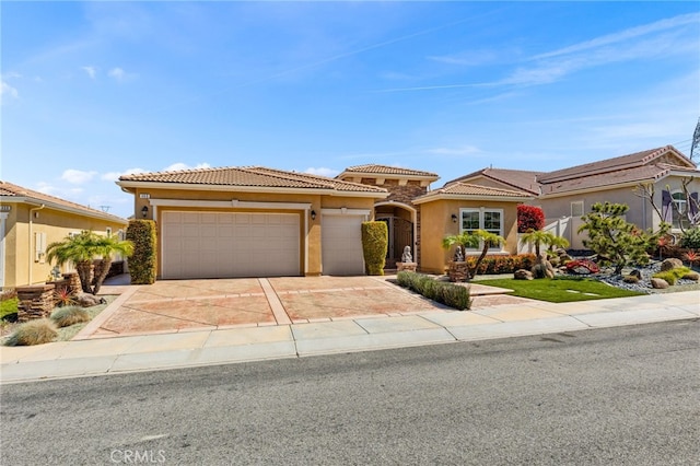 view of front facade featuring an attached garage, driveway, stucco siding, and a tile roof