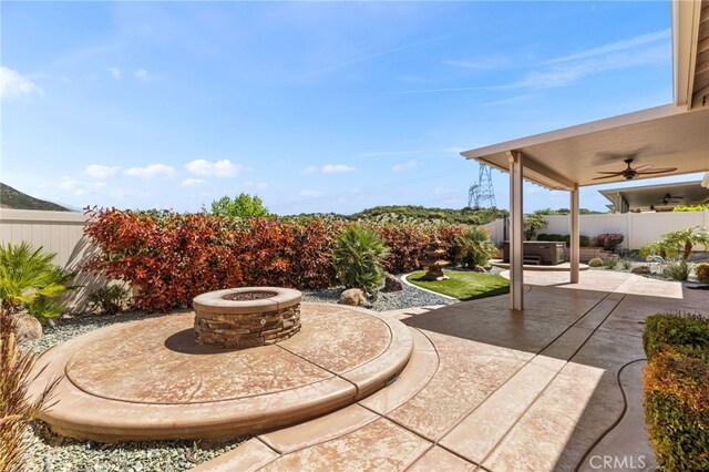 view of patio featuring an outdoor fire pit, ceiling fan, and a fenced backyard
