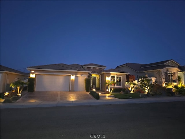 prairie-style house with a garage, driveway, and stucco siding