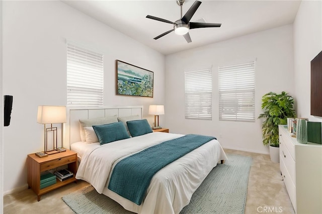 bedroom featuring light carpet, baseboards, and a ceiling fan