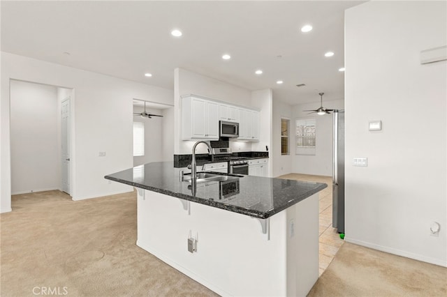 kitchen featuring stainless steel appliances, a sink, light carpet, and a ceiling fan