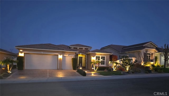 view of front facade with a garage, stucco siding, driveway, and a tile roof
