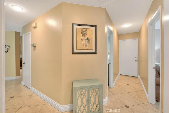 hall featuring light tile patterned flooring and baseboards