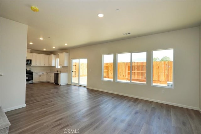 unfurnished living room featuring dark wood-style flooring, visible vents, and recessed lighting