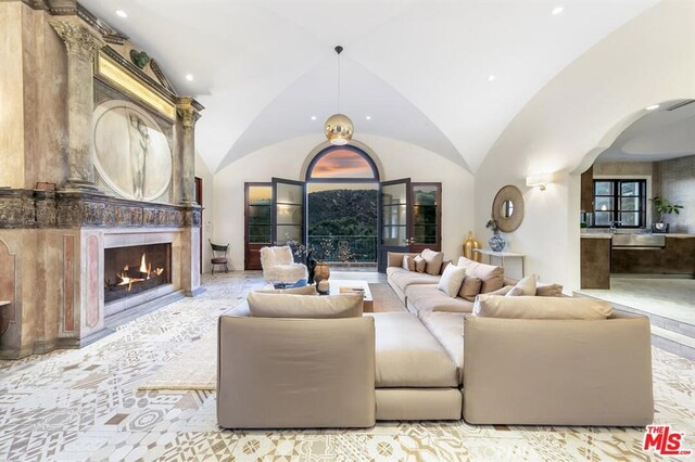 living room featuring a lit fireplace, arched walkways, lofted ceiling, and recessed lighting